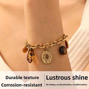 Detail view of gold Cuban chain bracelet with vintage charms and tiger eye bead