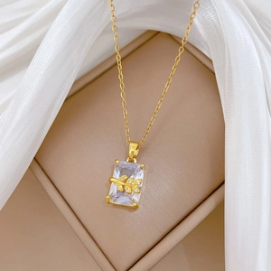 Detailed close-up of golden leaf pendant with crystal gems on elegant white silk background