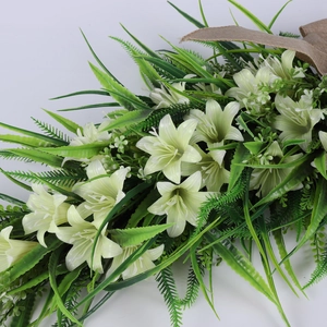 Detailed view of artificial white lily bouquet with green leaves and burlap ribbon decoration