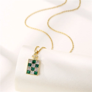 Collier flacon de parfum doré avec cristaux en damier vert et clair sur un support élégant