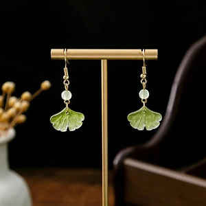 Macro shot of ginkgo leaf earrings with green beads and gold hooks in Chinese style