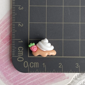Macro detail of a resin strawberry cream waffle charm showing size on a scale mat