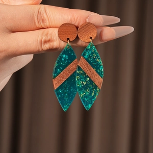 Gros plan de boucles d'oreilles ovales en bois avec résine verte et feuilles d'or