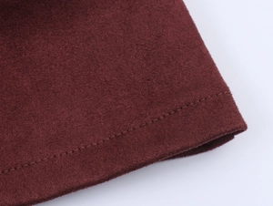 Detail shot of heavy suede fabric with precise stitching in deep burgundy color