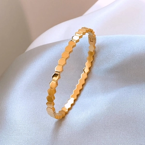 Polished gold honeycomb titanium steel bangle with a minimalist geometric open design