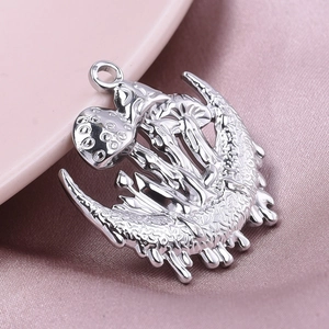 Detailed close-up of a silver crescent moon and mushroom charm on soft satin fabric