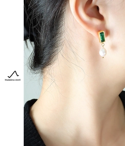 Detail of vintage gold earrings with green zircon and white pearl on model