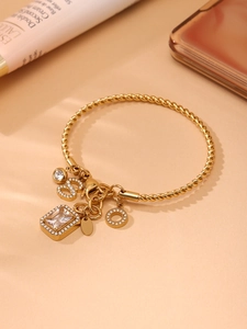 Macro detail of 18K gold braided twisted bracelet with sparkling CZ crystal pendants