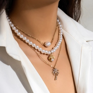 Detailed layered necklace featuring faux pearls, gold sea shell, and a sparkling coconut tree