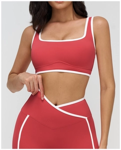 Close-up of red yoga bra with square neck and white contrast piping and cross waist detail