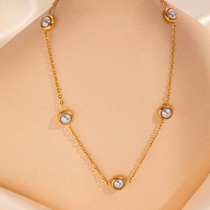 Detail of gold chain necklace with five grey pearls shown on a model neck display