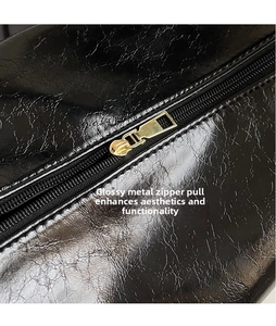 Close-up of black pleated faux leather texture with a polished gold metal zipper puller
