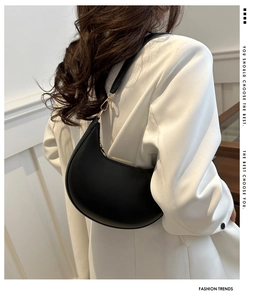 Fashionable black hobo underarm bag with gold hardware styled on a white blazer