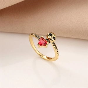 Detail of gold skull ring with red heart stone and black zircons on silk fabric