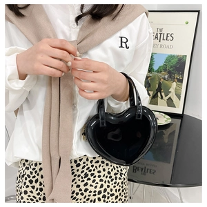 Close-up of a glossy black heart-shaped handbag styled with a trendy outfit