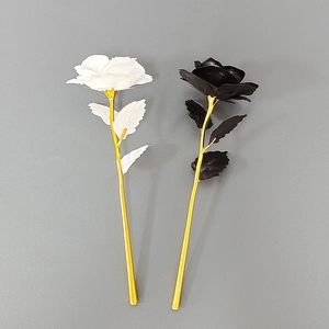 Detailed view of black and white artificial roses with golden stems for gift decor