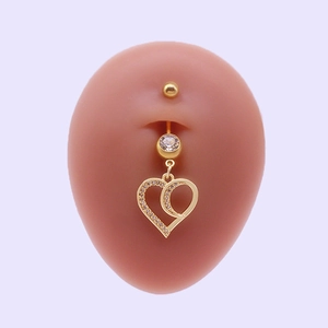 Piercing de nombril coeur doré avec cristaux sur un mannequin fond violet pastel