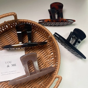 Elegant butterfly claw hair clips in tortoise shell and black finish on a wicker basket