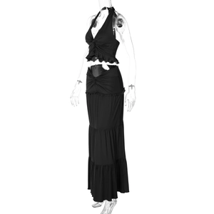 Detail of black two-piece halter set with twist knot design and ruffled layered maxi skirt
