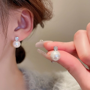 Détail de boucles d'oreilles perles en argent avec zircone cubique sur une oreille