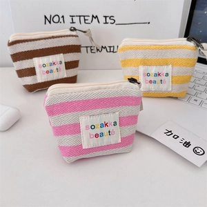 Three colorful striped canvas mini makeup bags with rainbow logo and zipper closure