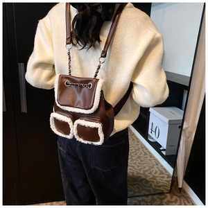 Detalle de mini mochila de cuero marrón con ribete de pelo sintético blanco en un modelo