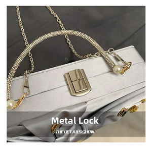 Detail of silver satin evening bag with sparkling rhinestone handle and gold metal lock