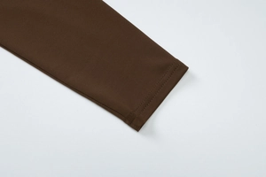 Dettaglio ravvicinato della manica in maglia marrone scuro con doppia cucitura rifinita