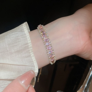 Detailed close-up of pink zircon pear-shaped gemstones on a gold adjustable bracelet