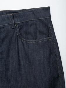 Dettaglio dei jeans a vita alta blu scuro con cuciture gialle e tasche anteriori