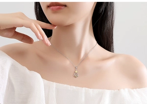 Detail of s925 silver necklace featuring diamond-shaped pendant on female model