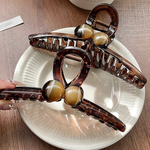 Detail of amber tortoiseshell hair claws with marble beads in a ceramic tray