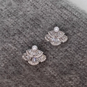 Vue détaillée de boucles d'oreilles en argent en éventail avec zircons et perles sur tissu