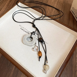 Détail d'un collier bohème avec anneau blanc et cœur argenté sur plateau en bois