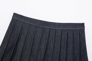 Detailed close-up of dark blue denim pleated skirt waistband with white stitching