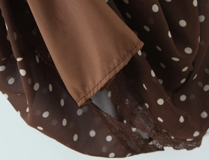 Détail du tissu en mousseline marron à pois blancs et bordure en dentelle marron délicate
