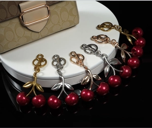 Macro detail of cherry bag charms in gold and silver finish with red glitter resin