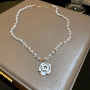 Dettaglio della collana di perle barocche con pendente a forma di camelia bianca e grani d'oro