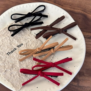 Set of four velvet bow hair clips in red, black, and brown on a white ceramic plate