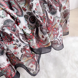 Detail of paisley print silk scarf fabric with elegant black sheer mesh lace trim
