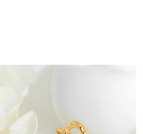Close-up of a warm golden irregular wavy textured ring placed on a white curved ceramic dish