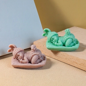 Detail of sleeping baby candles with knitted texture in pink and mint green colors