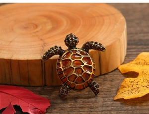 Detailed macro view of vintage sea turtle brooch with orange enamel and brown rhinestones