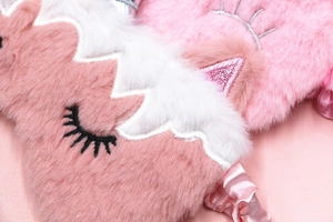 Close-up of pink unicorn plush eye mask with soft fur texture and embroidered eyelashes
