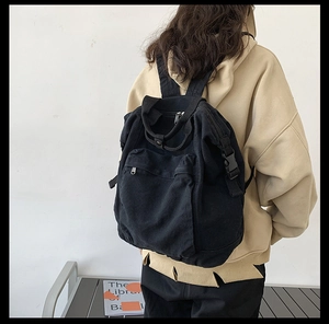 Minimalist black washed canvas backpack shown from behind on a model for a relaxed casual look