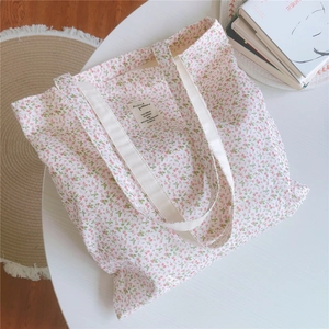 Nahaufnahme kleiner Blumenmuster und Stoffetikett auf einer cremefarbenen Baumwolltasche