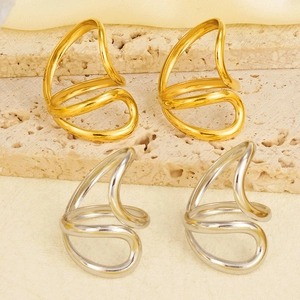 Detailed view of irregular 18k gold and silver ear cuffs on a beige stone base