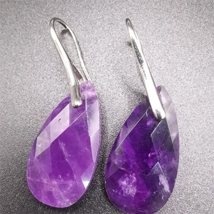 Macro detail of faceted purple amethyst teardrop earrings with silver metal hooks
