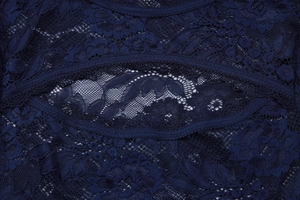 Detail van donkerblauwe kantstof met bloemig borduurwerk en opengewerkte textuur