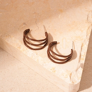 Macro shot of dark brown triple-layered C-shaped glaze earrings on a natural stone base